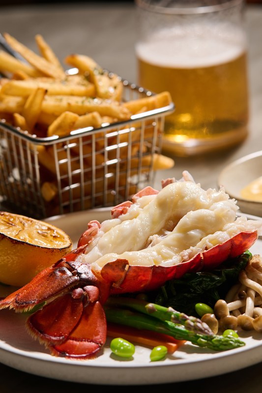 Butter poached lobster tail in the shell served with furikake fries, charred lemon, asparagus and enoki mushrooms at Morimoto by Sea