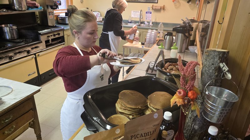 Kitchen staff serving stacks of pancakes and sausage in the Elmhurst Outdoors lodge